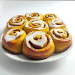 To make pumpkin spice cinnamon rolls, you need: - 2 cups all-purpose flour - 2 tablespoons granulated sugar - 1 tablespoon baking powder - 3/4 cup pumpkin puree - 1/2 cup milk - 1/4 cup unsalted butter, melted - 1 large egg These items create a soft and fluffy dough. The pumpkin puree gives it a rich flavor and moist texture. For the filling and icing, gather these ingredients: - 1/2 cup brown sugar, packed - 2 teaspoons cinnamon - 1/4 cup unsalted butter, softened - 1 cup powdered sugar - 2 tablespoons milk - 1/2 teaspoon vanilla extract The brown sugar and cinnamon create a sweet and warm filling. The icing adds a creamy finish to each roll. This combination makes every bite a delightful treat. - Mixing dry ingredients: Start by adding 2 cups of all-purpose flour, 2 tablespoons of granulated sugar, 1 tablespoon of baking powder, 1 teaspoon of cinnamon, 1/2 teaspoon of nutmeg, and 1/4 teaspoon of salt into a large bowl. Whisk these together until they blend well. - Combining wet ingredients: In a separate bowl, mix together 3/4 cup of pumpkin puree, 1/2 cup of milk, 1/4 cup of melted unsalted butter, and 1 large egg. Stir until the mixture is smooth and creamy. - Forming the dough: Gradually add the wet mix to the dry mix. Stir until just combined to form a soft dough. Be careful not to overmix; a little lumpiness is okay. - Rolling out the dough: On a lightly floured surface, take the dough and roll it into a rectangle. Aim for about 1/4 inch thick. This will help create nice, fluffy rolls. - Spreading butter and adding filling: Spread 1/4 cup of softened unsalted butter over the dough. Leave a small border around the edges. In a small bowl, mix 1/2 cup of packed brown sugar and 2 teaspoons of cinnamon. Sprinkle this mixture evenly over the buttered dough. - Rolling and slicing the dough: Starting from one long edge, carefully roll the dough tightly into a log. Pinch the seam to seal it. Slice the log into 1-inch thick pieces to make individual rolls. - Preheating the air fryer: Set your air fryer to 320°F (160°C) and let it preheat. This step is vital for even cooking. - Arranging rolls in the basket: Lightly grease the air fryer basket or line it with parchment paper. Place the cinnamon rolls in the basket, leaving space between them for expansion. You might need to do this in batches. - Air frying process: Cook the rolls for about 10-12 minutes. They should turn golden brown and be cooked through. Keep an eye on them to ensure they don’t overcook. Now enjoy the sweet aroma of pumpkin spice wafting through your kitchen! To avoid dry dough, use fresh flour and measure correctly. Too much flour makes dough tough. Mix the wet and dry ingredients until just combined. Over-mixing can lead to dryness. For even cooking in the air fryer, do not crowd the basket. Leave space between each roll. This allows hot air to circulate and cook them evenly. You can air fry in batches if needed. Timing is key for best results. Start checking the rolls around 10 minutes of cooking. They should be golden brown and cooked through. If they need more time, check every minute until done. For presentation, serve the rolls warm on a pretty platter. Drizzle extra icing on top for a nice touch. Adding toasted pecans gives a crunchy texture and boosts flavor. Pair your pumpkin spice cinnamon rolls with warm apple cider or a rich cup of coffee. These drinks enhance the sweet and spiced flavors, creating a delightful experience. {{image_2}} You can make your pumpkin spice cinnamon rolls even more fun! Try adding nuts or chocolate chips to the filling. Chopped walnuts or pecans add a nice crunch. If you prefer chocolate, use mini chocolate chips for a sweet surprise. You can also swap pumpkin puree for other flavors. Use applesauce for a fruity twist or mashed banana for a different taste. Each swap gives you a unique roll, keeping it fresh and exciting. Want to make these rolls gluten-free? Simply use a gluten-free flour blend. It works the same as all-purpose flour. Look for one with xanthan gum for the best results. For a vegan option, replace the egg with a flax egg. Mix one tablespoon of ground flaxseed with three tablespoons of water and let it sit until thick. Use almond milk or any plant-based milk instead of regular milk. Swap the butter for coconut oil or vegan butter, and enjoy your tasty treat! To keep your pumpkin spice cinnamon rolls fresh, store them properly. First, let the rolls cool down to room temperature. Then, place them in an airtight container. This helps keep them moist. You can store them in the fridge for up to five days. If you want to keep them longer, consider freezing them. For freezing, wrap each cinnamon roll tightly in plastic wrap. Then, place them in a freezer bag. Be sure to date the bag, so you remember when you made them. They can last in the freezer for up to three months. You have two great options for reheating: the microwave or the air fryer. The microwave is quick. Just place the roll on a microwave-safe plate. Heat it for about 10 to 15 seconds. This warms it up but may make it a bit soft. The air fryer is my favorite method. It keeps the rolls fluffy and adds a nice crisp. Preheat your air fryer to 320°F (160°C). Place the cinnamon rolls in the basket and heat for about 3 to 5 minutes. This method keeps the texture and flavor intact. Enjoy your warm and gooey treat! Yes, you can bake these rolls in a traditional oven. Preheat your oven to 350°F (175°C). Place the rolls on a baking sheet and bake for about 20-25 minutes or until golden brown. The air fryer gives them a nice crisp, but the oven works well too. Your cinnamon rolls are done when they are golden brown on top. You can also insert a toothpick in the center. If it comes out clean, they are ready. Keep an eye on them to avoid overcooking. If you don't have pumpkin puree, you can use applesauce or mashed bananas. Both options add moisture and sweetness. Just remember that the flavor will change slightly. Absolutely! You can make the dough ahead of time. After forming it, wrap it tightly in plastic wrap. Store it in the fridge for up to 24 hours. When ready, let it come to room temperature before rolling it out. These pumpkin spice cinnamon rolls are easy to make and fun to enjoy. We covered ingredients like flour and pumpkin puree and steps from mixing to cooking in an air fryer. Follow tips to get perfect rolls every time. You can even try variations, like adding nuts or gluten-free swaps, to fit your taste. Store leftover rolls correctly and reheat for the best flavor. Now, you’re ready to impress family and friends with a delicious treat. Enjoy baking and savoring every bite!